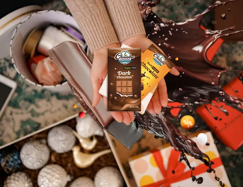 Hands holding two dark chocolate bars over a basket of holiday ornaments and gift boxes with a chocolate splash.
