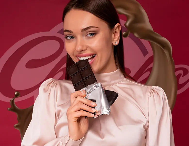 A woman smiling and holding a dark chocolate bar against a maroon background with dynamic chocolate swirls.